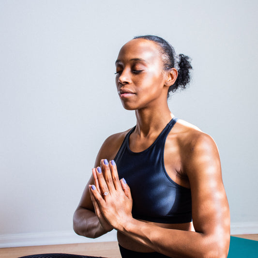 Person of color meditating with their eyes closed peacefully. 